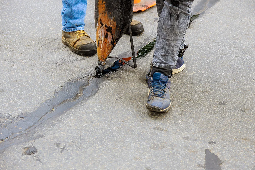construction worker repairing a crack with tar