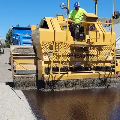 man chip sealing a road in a chip seal machine